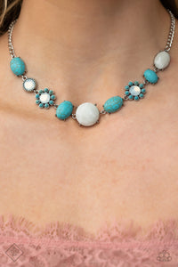 A collection of turquoise stones and white opalescent beads are featured in a range of pronged silver fittings and floral patterns, falling along the neckline in an artisanal display. The haphazard placement of each element further emphasizes their handcrafted charm, as the opalescent beads bring a hint of shimmer to the design. Features an adjustable clasp closure. As the stone elements in this piece are natural, some color variation is normal.
