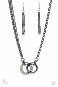 A pair of beveled gunmetal hoops interlock at the center of the collarbone, creating an eye-catching pendant. One hoop is coated in white rhinestones, while the other showcases a high-sheen finish, providing an intriguing collision of texture. The interlocking pendant is attached to a thick gunmetal chain, with a pair of daintier gunmetal chains added along one side for an asymmetrical finish. Features an adjustable clasp closure.  Sold as one individual necklace. Includes one pair of matching earrin