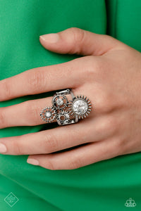 Centered atop a pair of arcing silver bands, four gear pendants with varying textures, details, sizes, and a dusting of gems climb up the finger for a steampunk-styled centerpiece. Features a stretchy band for a flexible fit.  Sold as one individual ring.