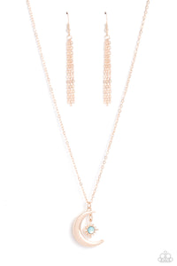 A glassy blue bead is pressed into the center of a three-dimensional rose gold star that dances from the top of a rose gold crescent moon pendant, creating a celestial pendant at the bottom of a dainty rose gold chain. Features an adjustable clasp closure. 