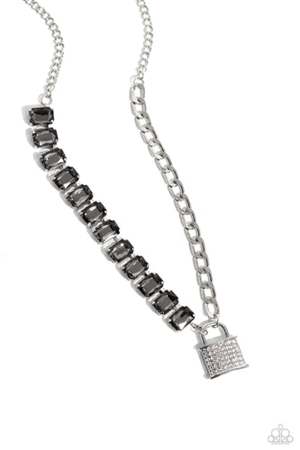 Infused on a classic silver chain, a strand of thick silver curb chain, and a collection of exaggerated, smoky radiant-cut gems in silver pronged fittings combine to create a collision of industrial color around the neckline. An oversized silver lock charm, embossed in white rhinestones, dangles from the gritty display for a touch of soft glitz to the design. Features an adjustable clasp closure. 