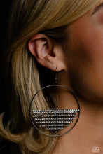 Load image into Gallery viewer, A curtain of white rhinestones is stretched between the edges of a skinny, oversized gunmetal hoop, creating a shimmering display. The rhinestones taper towards the center as they sway and cascade, adding sparkly movement for a fierce industrial finish. Earring attaches to a standard fishhook fitting. 
