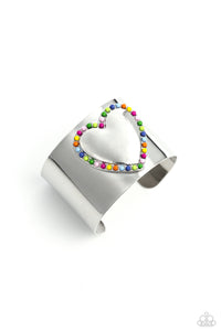 Featuring Rose Violet, light pink, Classic Green, Kohlrabi, Persian Jewel, Summer Song, High Visibility, red, and orange beads, the center of a thick silver cuff swoops and curls into a charming heart, creating a retro-inspired fashion.
