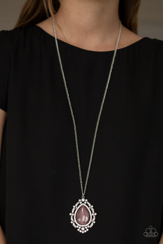 Dotted in glittery white rhinestones, leafy silver frames nestle around a glowing purple cat's eye teardrop center, creating a regal pendant at the bottom of a lengthened silver chain. Features an adjustable clasp closure.  Sold as one individual necklace. Includes one pair of matching earrings.