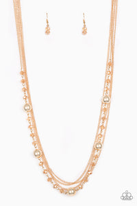 Infused with rows of shimmery gold chains, a strand of golden crystal-like beads and classic gold accents drape across the chest for a regal finish. Features an adjustable clasp closure.  Sold as one individual necklace. Includes one pair of matching earrings.