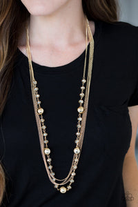 Infused with rows of shimmery gold chains, a strand of golden crystal-like beads and classic gold accents drape across the chest for a regal finish. Features an adjustable clasp closure.  Sold as one individual necklace. Includes one pair of matching earrings.