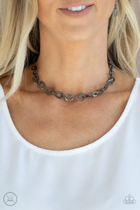 Embossed in a metallic crocodile-like print, asymmetrical gunmetal links delicately connect around the neck for a wild industrial inspired look. Features an adjustable clasp closure.