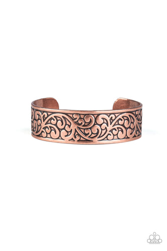 Brushed in an antiqued shimmer, vine-like filigree is embossed across the front of a thick copper cuff for a whimsical look.