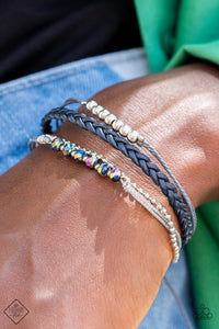 Mismatched strands of sparkly silver thread, braided navy blue leather cording, and gray string fall into seamless layers as they wrap around the wrist. A strand of dainty silver ball chain is added to the mix, as classic silver beads and oil spill crystal-like gems embellish the gray and silver strands in a stellar finish. Features an adjustable sliding knot closure.  Sold as one individual bracelet.  New Kit Fashion Fix