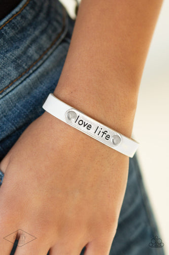 A silver plate engraved with the inspirational phrase “love life” is studded in place along a skinny strip of white leather. Brushed in a shiny finish, the dainty band wraps around the wrist in a simply seasonal style. Features an adjustable snap closure.  Sold as one individual bracelet.  New Kit FANFAVORITE This Fan Favorite is back in the spotlight at the request of our 2020 Life of the Party member with Black Diamond Access, Britney G.
