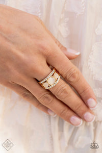 A trio of round champagne cat’s eye stones is set in gold pronged fittings between two dainty gold bands that are encrusted in rows of glassy white rhinestones, coalescing into an elegantly layered centerpiece atop the finger. Features a dainty stretchy band for a flexible fit.  Sold as one individual ring.  New Kit Fashion Fix