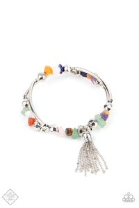 An earthy collection of faceted silver beads, raw cut multicolored rock beads, and cylindrical silver accents are threaded along a coiled wire around the wrist for a grounding pop of color. A shimmery silver chain tassel swings from one end of the spiral, adding a hint of flirtatious movement to the piece.  Sold as one individual bracelet.