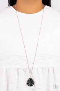 Featuring a shell-like iridescence, shimmery flecks are sprinkled along a shiny black backdrop inside of a glassy casing. The colorful teardrop swings from the bottom of an extended silver chain, creating a summery pendant. Features an adjustable clasp closure.  Sold as one individual necklace. Includes one pair of matching earrings.
