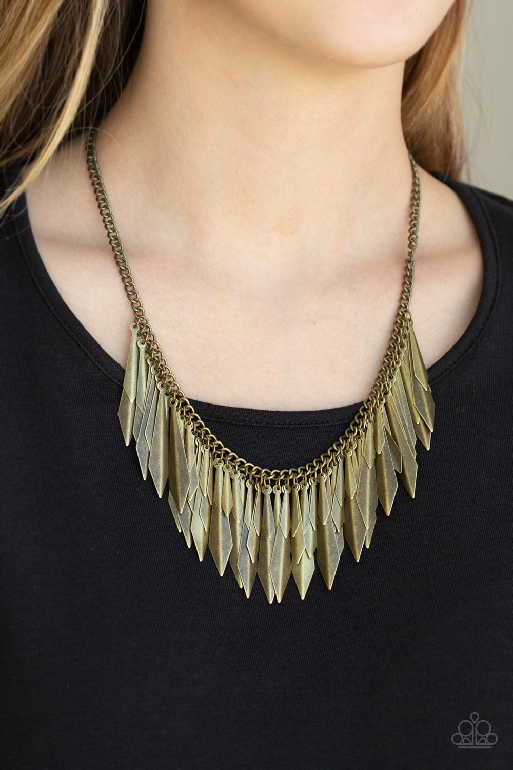 A collection of flared brass daggers swing from the bottom of a glistening brass chain, creating an edgy fringe below the collar. Featuring a subtle crease down the center, the shimmery discs gradually increase in size as they drip from the chain, adding an irresistible industrial flair to the look. Features an adjustable clasp closure.