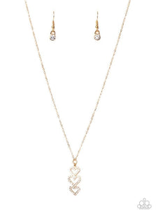 Encrusted in sparkly white rhinestones, a trio of golden heart frames delicately stack into a charming pendant that swings from a dainty gold chain below the collar for a flirty finish. Features an adjustable clasp closure.