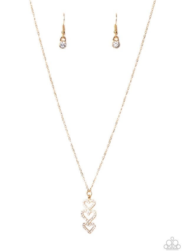 Encrusted in sparkly white rhinestones, a trio of golden heart frames delicately stack into a charming pendant that swings from a dainty gold chain below the collar for a flirty finish. Features an adjustable clasp closure.